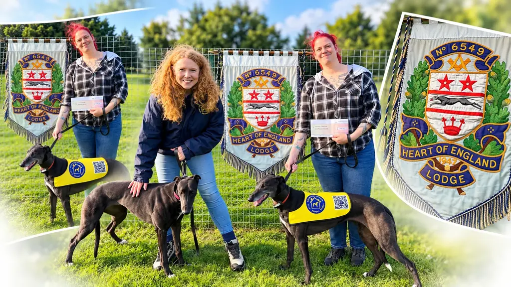 Heart of England Lodge No. 6549 presents a £1,000 donation to Home Run Hounds greyhound rescue charity, with two retired greyhounds and the Lodge banner featuring a black greyhound.