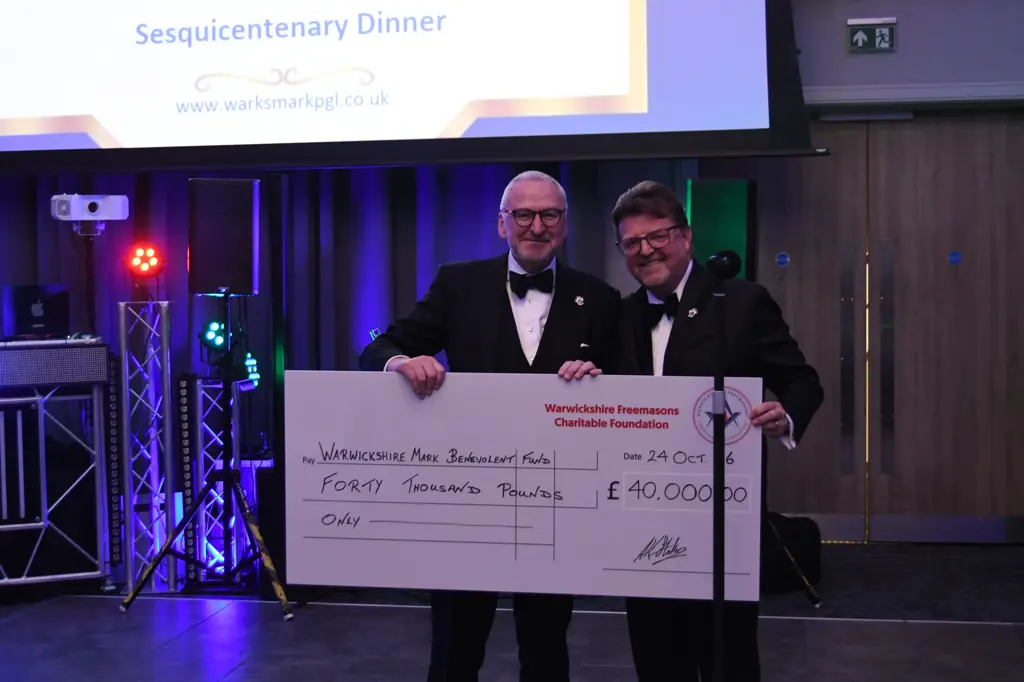 RW Bro. Philip Hall presents a £40,000 cheque to W. Bro. Andrew Armbrister for the Warwickshire Mark Masons Benevolent Fund at the Mark Province's 150th anniversary celebration.