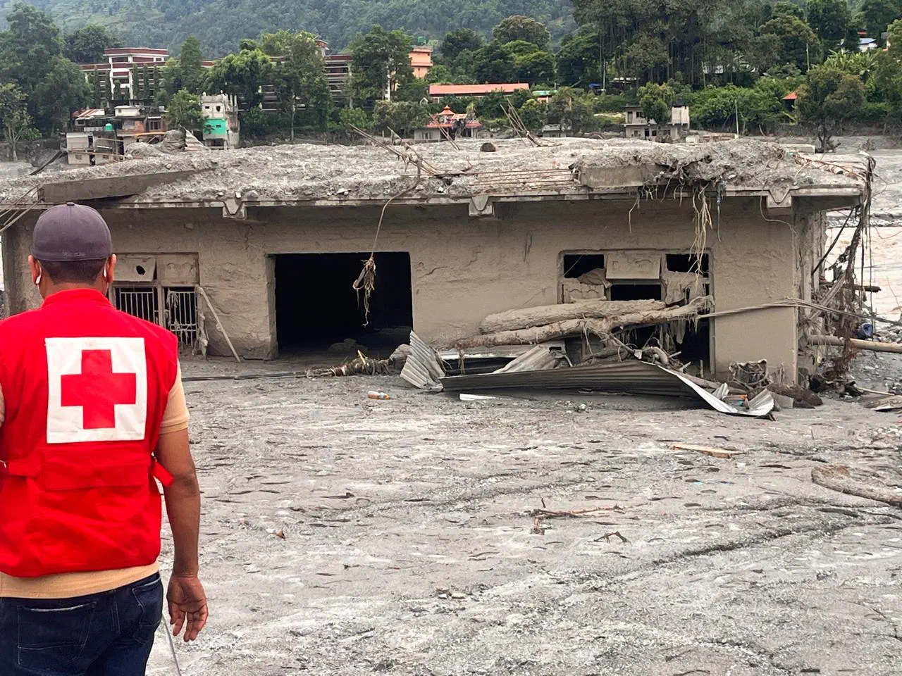 The attached photograph shows a Red Cross worker on the ground in the Nuwakot area in Nepal after the flash flood.